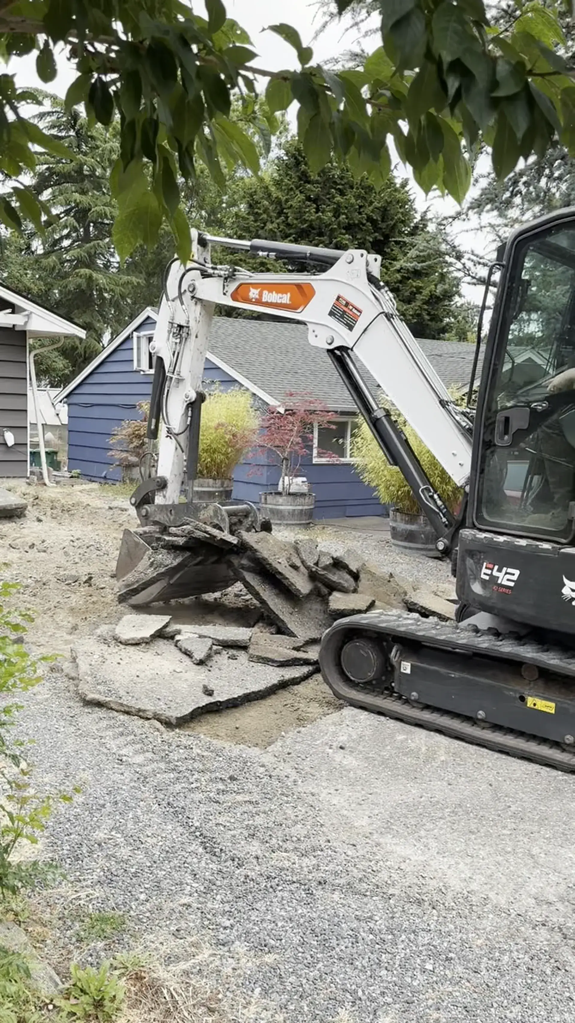 Bobcat E42 excavator prying up old asphalt driveway in Edmonds, WA