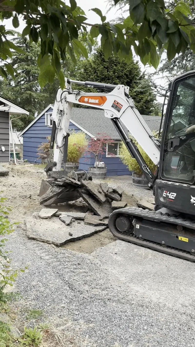 Bobcat E42 excavator prying up old asphalt driveway in Edmonds, WA
