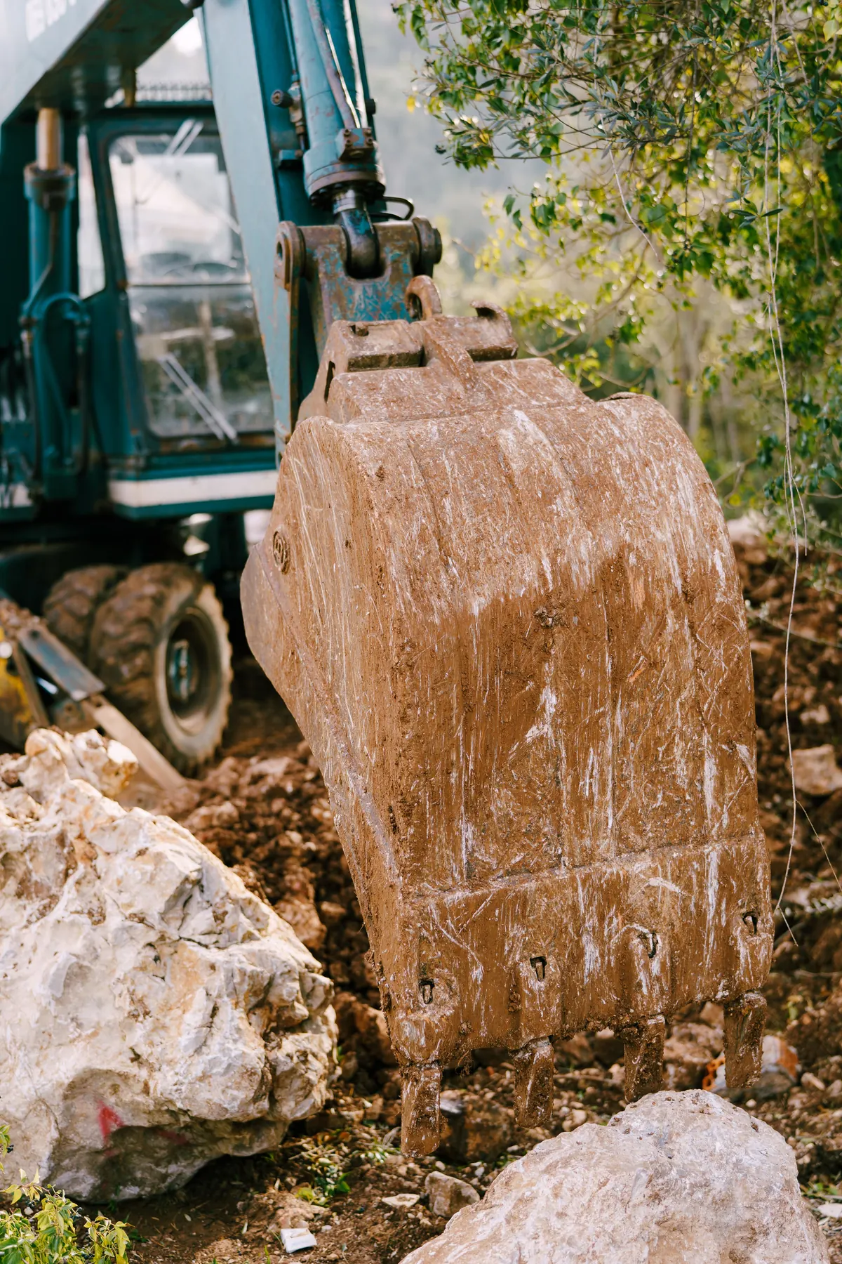 Excavator bucket cutting into rocky soil for a wall base